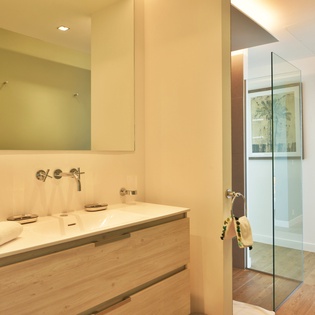 Your spacious bathroom features sleek design with a floating vanity, modern fixtures, and a luxurious glass-enclosed shower waiting for your arrival.