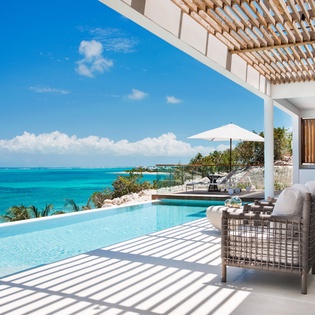 Stunning infinity pool meets turquoise ocean views in this modern paradise with elegant seating and seamless indoor-outdoor living.