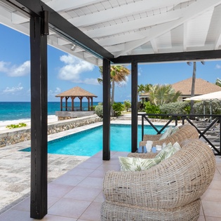 Settle into your private covered terrace overlooking the sparkling pool and pristine beach beyond. Feel the ocean breeze as you relax in cozy wicker seating with turquoise waters and swaying palms just steps away.