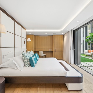 Sink into this luxurious floating bed while natural light pours through floor-to-ceiling windows overlooking your private terrace garden.