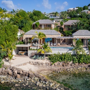 Stunning waterfront villa with private beach access, tropical gardens, and infinity pool overlooking crystal-clear Caribbean waters.
