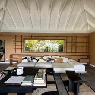 Unwind in your sophisticated living space with exposed beam ceilings, plush seating, and tropical garden views through the picture window.