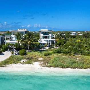 Beachfront paradise showcasing modern villas along pristine white sand and turquoise waters in a tropical coastal community.