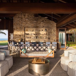 Unwind in your sophisticated lounge with handcrafted cocktails at the stone bar, luxurious seating, and stunning ocean vistas.