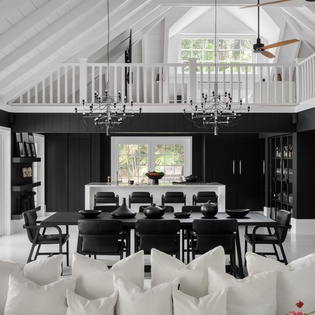 Your stunning open-plan living space features soaring white ceilings, sleek black cabinetry, and elegant dining for eight beneath sparkling chandeliers.