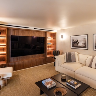 Sink into plush sofas facing your elegant entertainment wall, where warm wood tones and soft lighting create the perfect atmosphere for relaxing evenings.