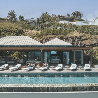 Modern villa with pristine pool surrounded by lush tropical landscape and contemporary architecture.