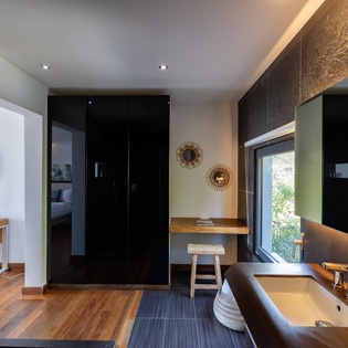 Unwind in your luxurious bathroom featuring warm wood accents, sleek dark cabinetry, and thoughtful lighting that creates a spa-like sanctuary.