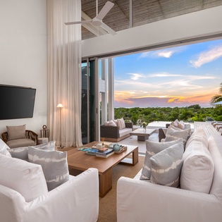 Sink into plush white sofas as gentle breezes flow through your open-air living space, where sunset views paint the sky beyond your private terrace.