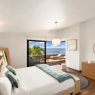 Wake up to stunning ocean views from your private bedroom, where warm wood tones and coastal-inspired decor create your perfect seaside retreat.