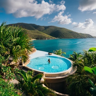 Breathtaking infinity pool overlooking pristine turquoise waters and lush tropical mountains creates the perfect paradise escape.