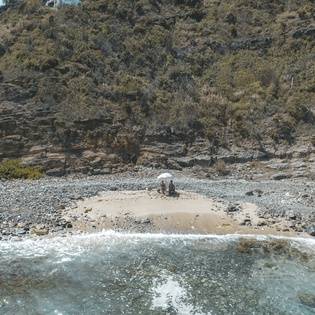 Secluded pebble beach nestled beneath dramatic cliffs, offering crystal-clear waters and peaceful natural surroundings away from crowds.