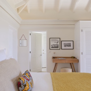 Rest easy in your coastal-inspired bedroom, where white beadboard ceilings and soft linens create a light, airy escape. The handcrafted desk and carefully curated coastal prints invite peaceful mornings.