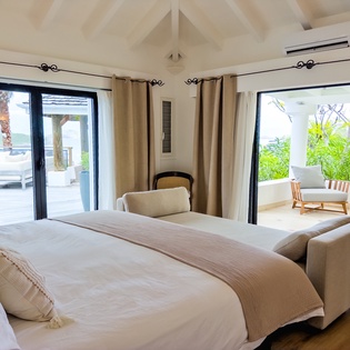 Wake up to gentle ocean breezes and tropical greenery framed by your private terrace doors. This airy, light-filled bedroom invites you to unwind in style with vaulted ceilings and serene coastal views.