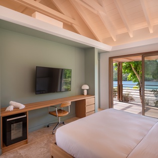 Wake up to stunning water views from your serene bedroom, where modern comfort meets coastal charm through floor-to-ceiling windows.