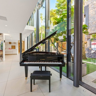 Step into elegance with a grand piano beckoning your musical moments in this stunning modern space with floor-to-ceiling windows.