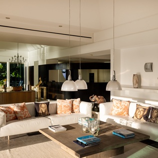 Sink into plush white sofas surrounded by curated art and warm pendant lighting in this sophisticated open-plan living space.