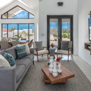 Settle into your open-concept living space flooded with natural light through soaring cathedral ceilings and enjoy serene views of lush tropical gardens just beyond your doors.