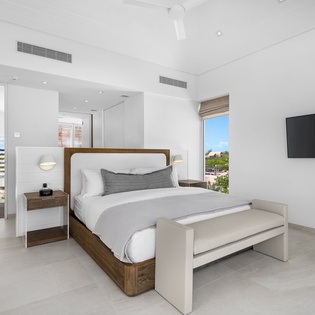 Sink into plush bedding with crisp linens in your serene retreat, where modern comfort meets stunning views through floor-to-ceiling windows.