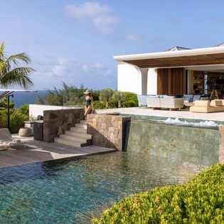 Stunning oceanfront villa with infinity pool, tropical landscaping, and modern architecture overlooking pristine waters.
