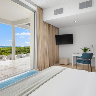 Your serene bedroom opens to stunning ocean views, with crisp linens and modern amenities creating the perfect tropical retreat.