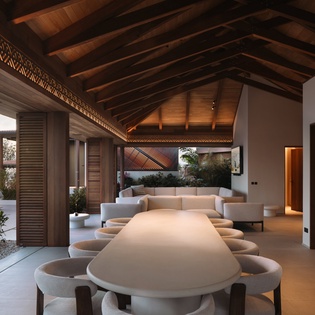 Relax in your sophisticated open-plan living space where exposed wood beams and modern furnishings create the perfect tropical retreat atmosphere.