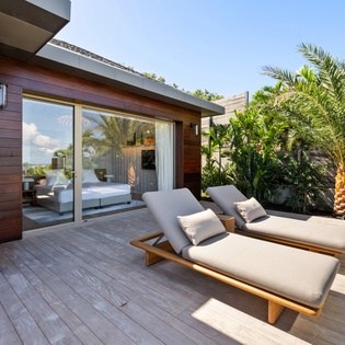 Unwind on your private deck with cushioned loungers and tropical palms creating your perfect sunny retreat.