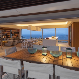 Unwind in your stunning open-concept living space with panoramic ocean views, where warm wood tones and modern design create the perfect backdrop for memorable evenings.