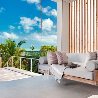 Relax on your private suspended swing daybed while soaking in tropical palm views and ocean breezes from this stunning terrace.
