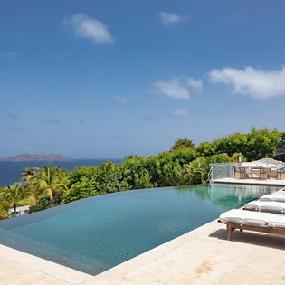 Bask in the infinity pool's serene edge while taking in sweeping ocean views and lush tropical gardens that frame your private paradise.