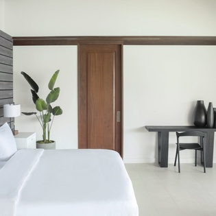 Unwind in your serene bedroom featuring crisp white linens, modern wood accents, and a workspace perfect for quiet moments.