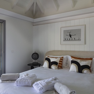 Rest peacefully in this serene bedroom where natural light streams through expansive windows, creating a calming retreat with crisp linens and modern coastal charm.