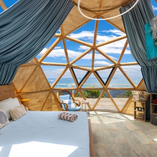 Relax in your airy geodesic dome with panoramic ocean views through geometric windows and a serene coastal breeze drifting in.