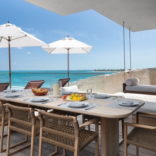 Your private terrace overlooks turquoise waters, where morning coffee and fresh fruit await at your oceanfront dining table.