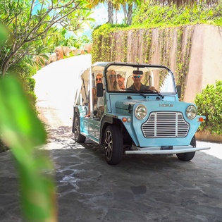 A charming vintage-style shuttle provides convenient transportation through lush tropical surroundings.