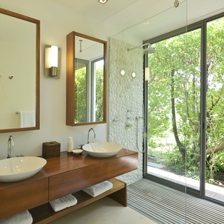 Your spa-like bathroom features dual vessel sinks and a luxurious glass shower with stunning garden views for your perfect morning routine.