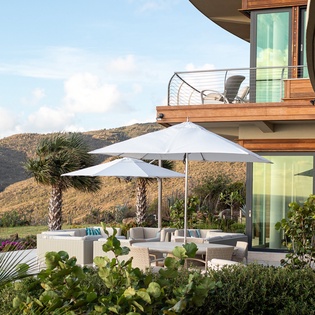 Modern hillside property featuring outdoor terrace with mountain backdrop and contemporary architecture.