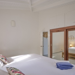 Sink into crisp white linens in your peaceful bedroom, where warm wood touches and natural light create the perfect retreat for restful nights.