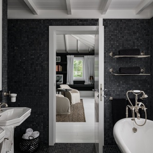 Immerse yourself in this luxurious spa-like bathroom featuring dark mosaic tiles, vintage fixtures, and a stunning freestanding tub for ultimate relaxation.