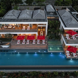 Stunning modern villa with expansive swimming pool, surrounded by lush tropical gardens and contemporary outdoor entertaining spaces.