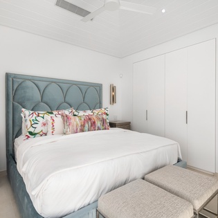 Slip into crisp linens beneath the elegant teal headboard, with ocean glimpses through your private doorway promising peaceful Caribbean dreams.