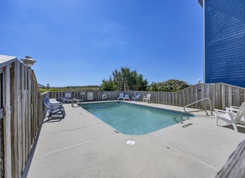 The private pool area features a spacious sun deck and ocean-side setting, surrounded by coastal vegetation and fenced for your privacy.