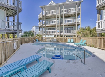 Private pool area nestled among coastal palms and neighboring beach homes, offering a peaceful spot to cool off and unwind between sandy adventures.
