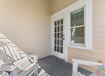 Step into your charming covered porch, where two inviting Adirondack chairs await your morning coffee or evening relaxation—your own cozy corner to unwind in coastal style.
