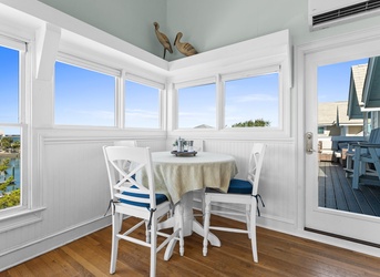 Bright coastal dining nook with panoramic water views and direct balcony access—your perfect spot for morning coffee or sunset dinners.