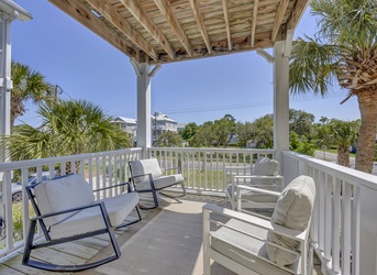 Relax in your private covered balcony, complete with rocking chairs and lounge seating overlooking lush palms and peaceful neighborhood views—perfect for morning coffee or evening unwinding.