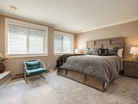Sink into plush bedding and feel the soft carpet beneath your feet as natural light filters through the blinds, inviting you to unwind in this cozy retreat.