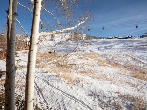 A winter mountain scene with ski lifts overhead and nearby lodges framing the snow-covered slopes. The property offers proximity to winter recreation areas and alpine surroundings.