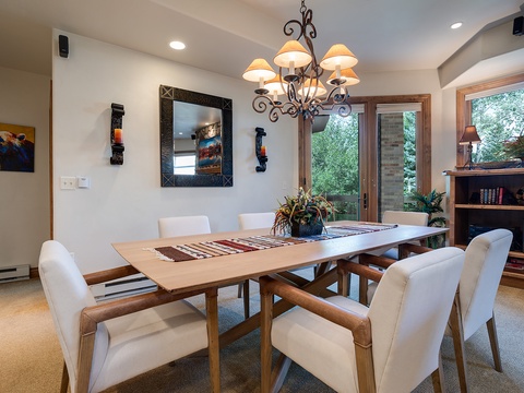 Gather around this elegant dining table under a warm chandelier, where your group can share memorable meals with natural light streaming through the glass doors.