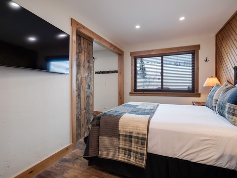Unwind in your cozy bedroom with rustic wood accents, a plush bed dressed in soft linens, and a peaceful mountain view from your window.